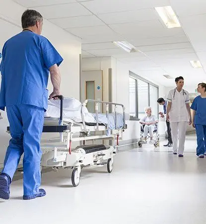 Enfeira empurrando maca no corredor de um hospital